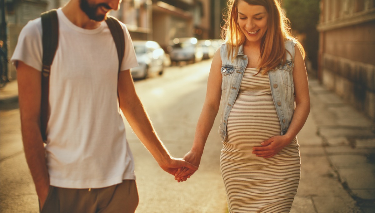 A pregnant woman and her partner holding hands 