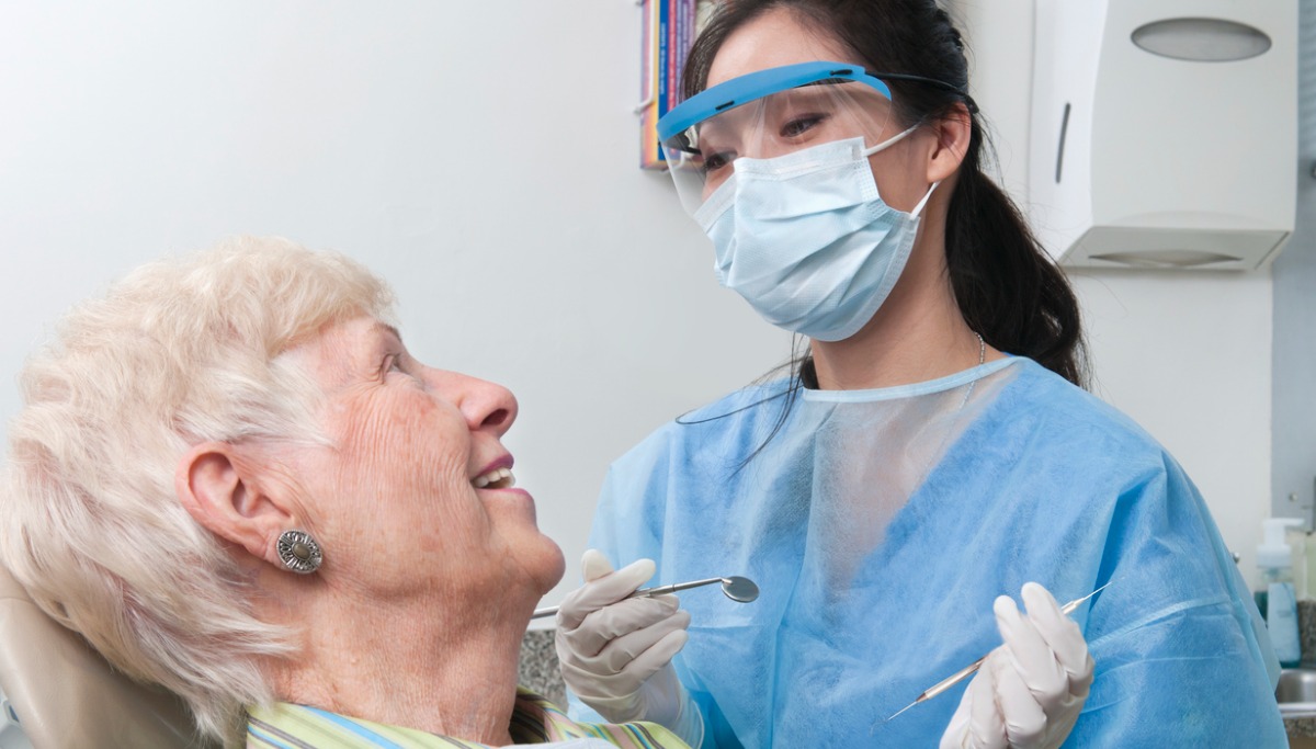 A woman looking up at a dentist and smiling