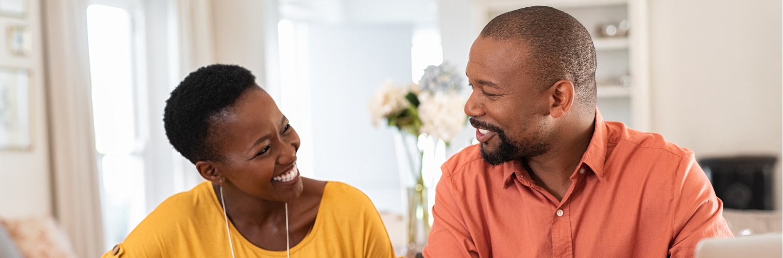 A couple is smiling while looking at a laptop together.
