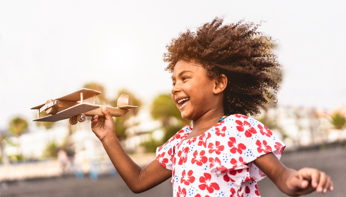 A small child playing with a wooden airplane