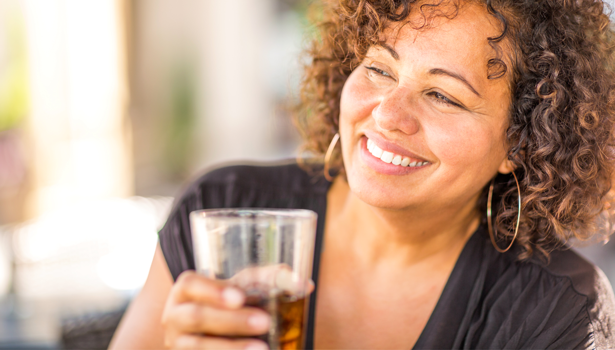 A woman smiling and drinking a soda