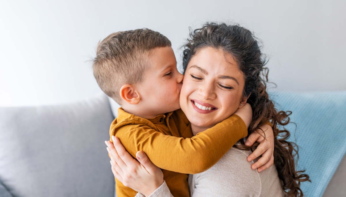 A small child kissing his mother on her cheek