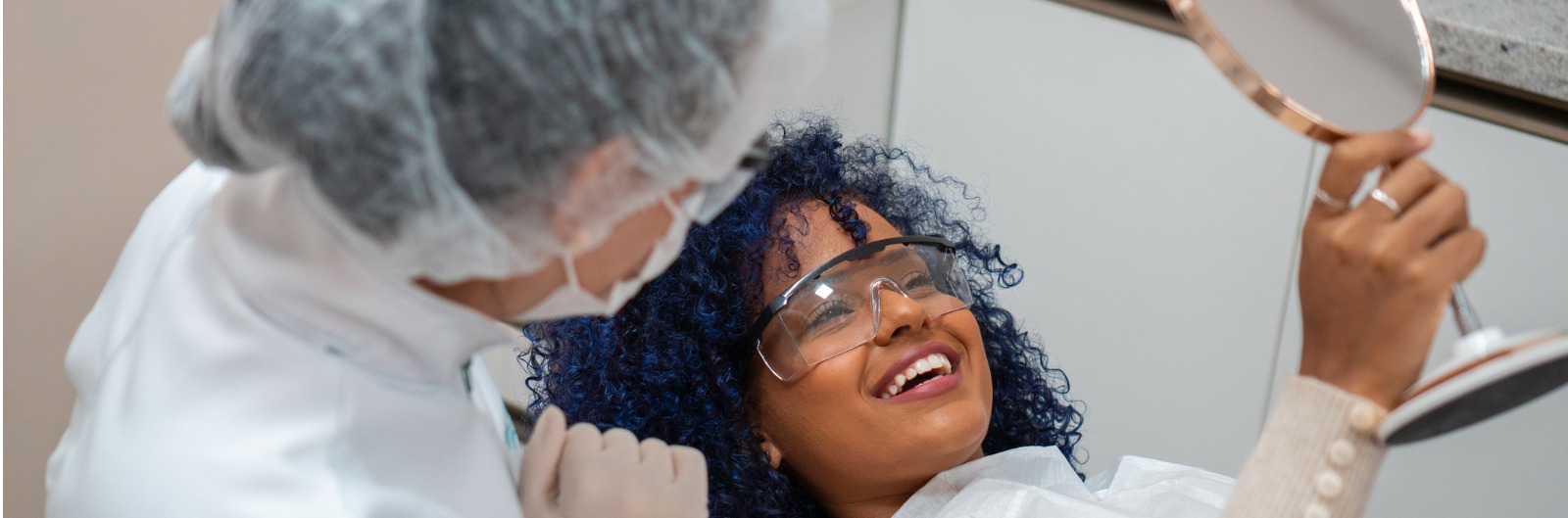A patient looking in a mirror and smiling after a dental procedure