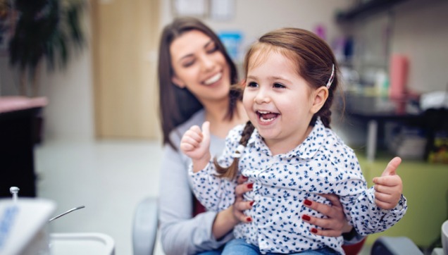 A young girl smiling while in a dentist office