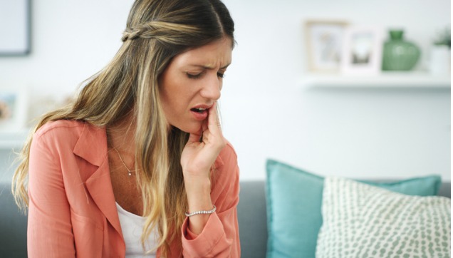 A woman holding her mouth in pain