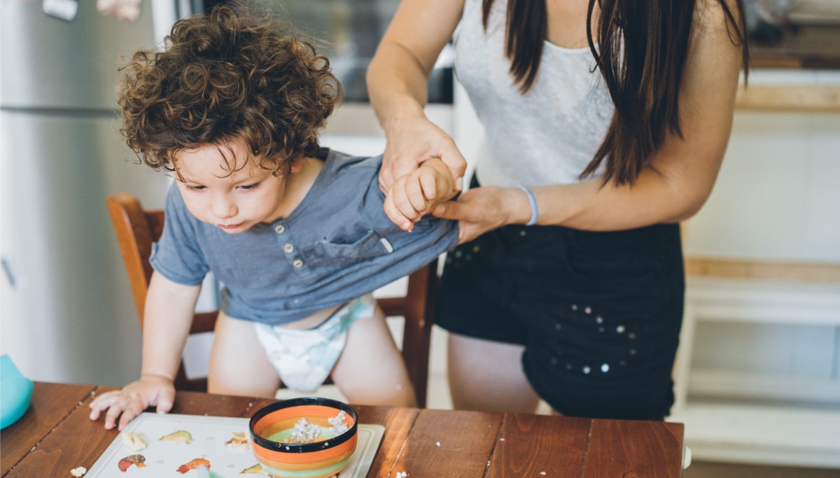 A mother cleaning up a toddler after eating