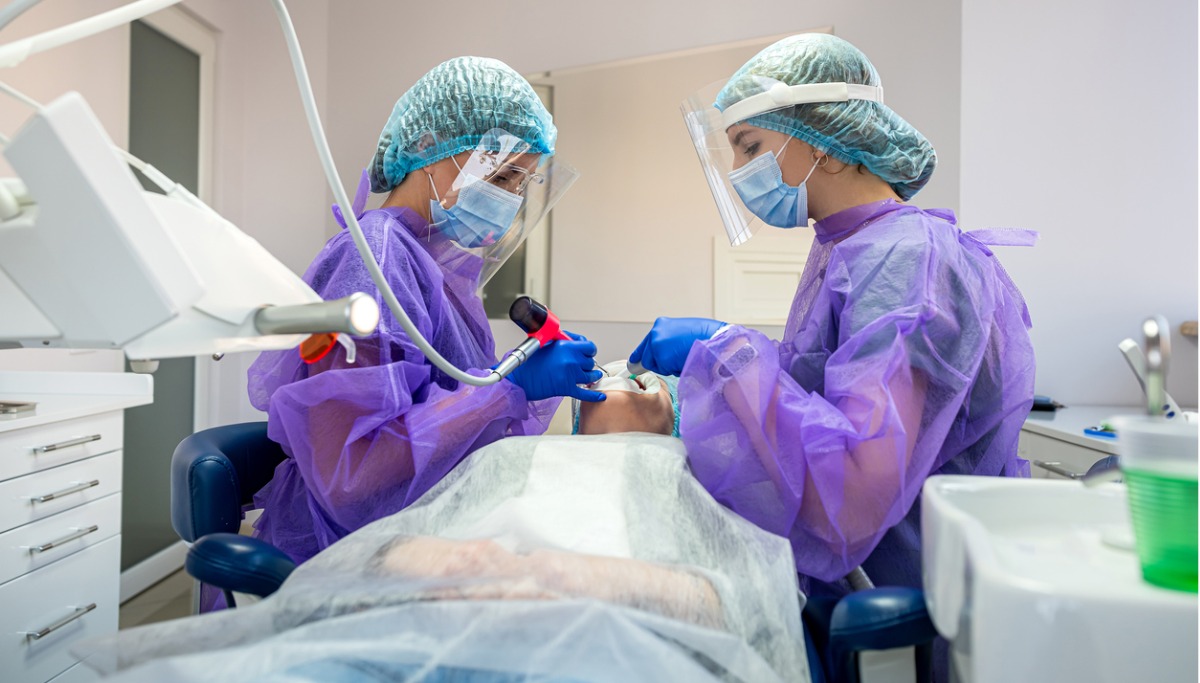 Two dentist conduct a tooth extraction on a patient