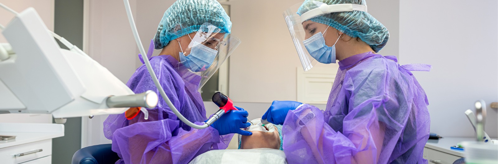 Two dentist conduct a tooth extraction on a patient