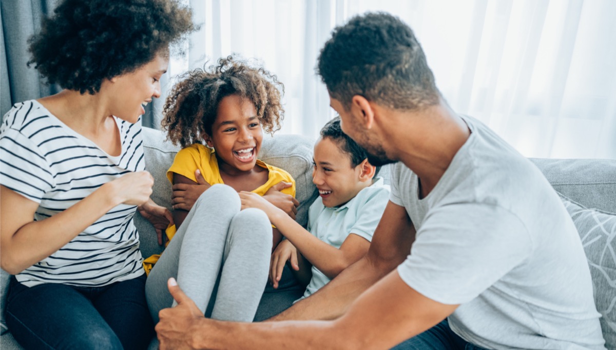 A family sitting on a couch and laughing