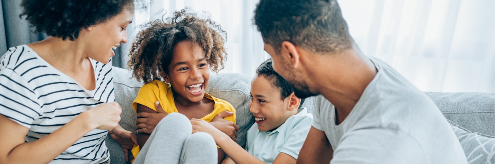 A family sitting on a couch and laughing