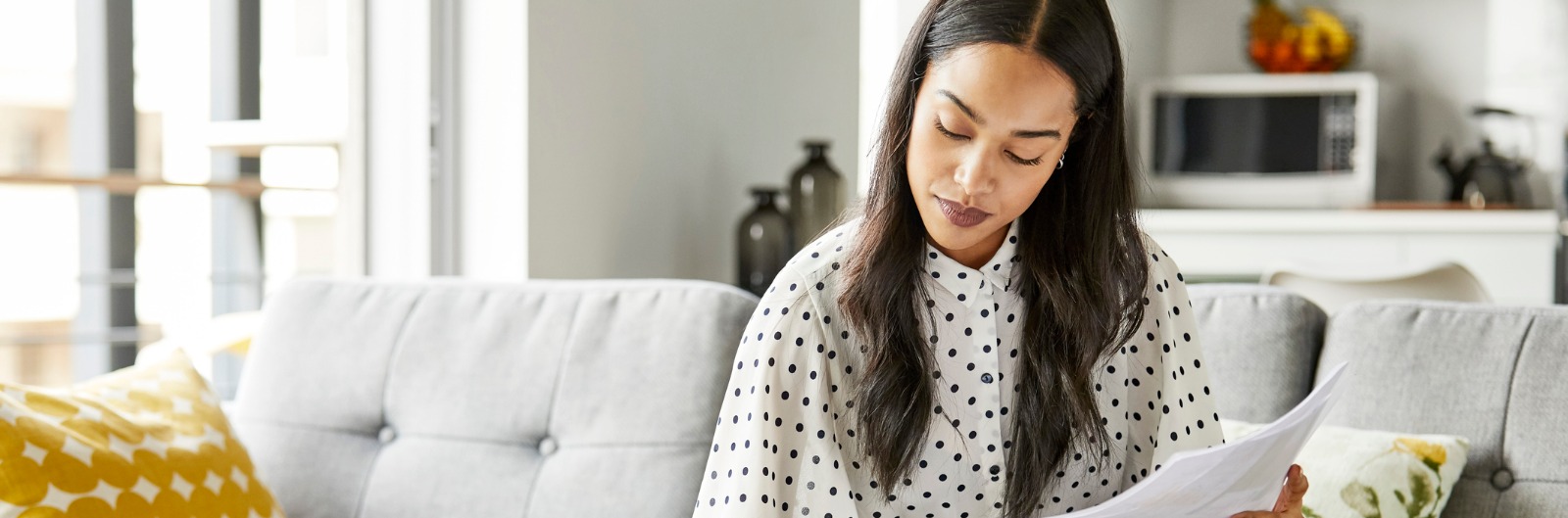 A women sitting on a couch and reviewing papers.