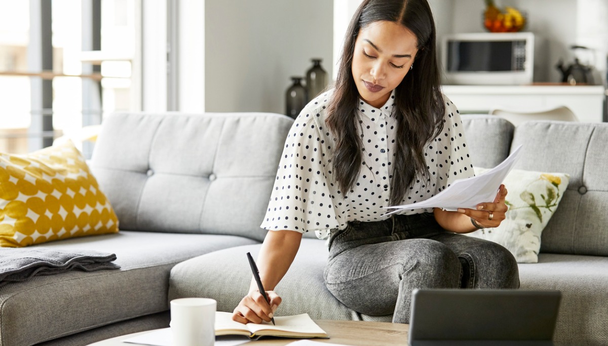 A women sitting on a couch and reviewing papers.
