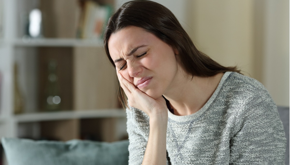 A woman holding the side of her face in pain