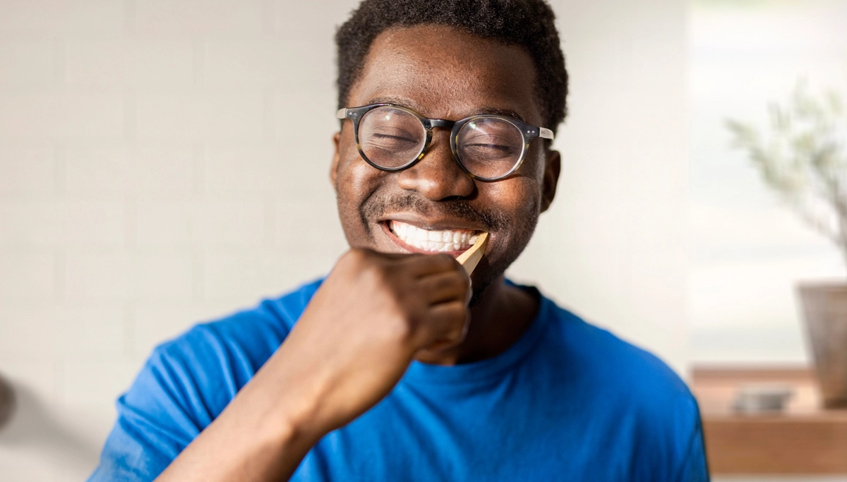 A man smiling and brushing his teeth