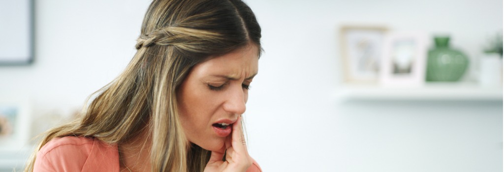 A woman holding her jaw in pain