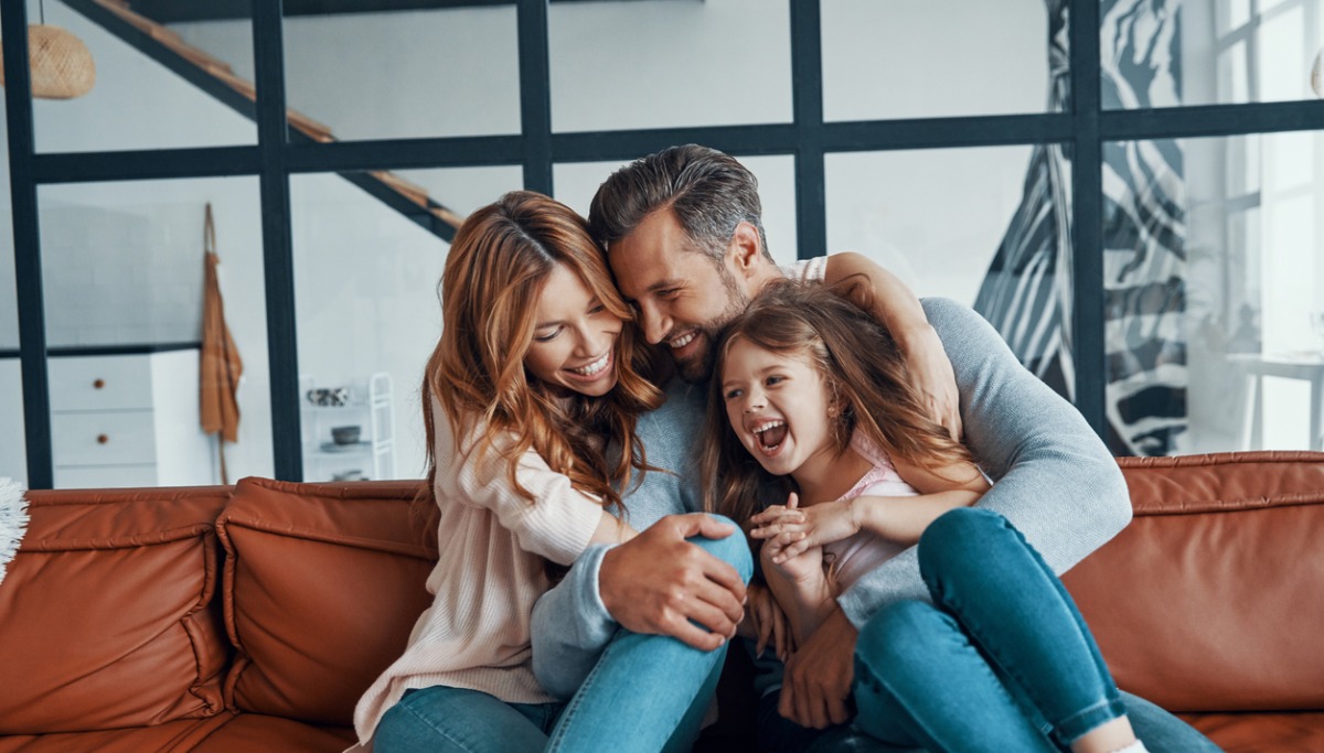 A family laughing and hugging on a coach