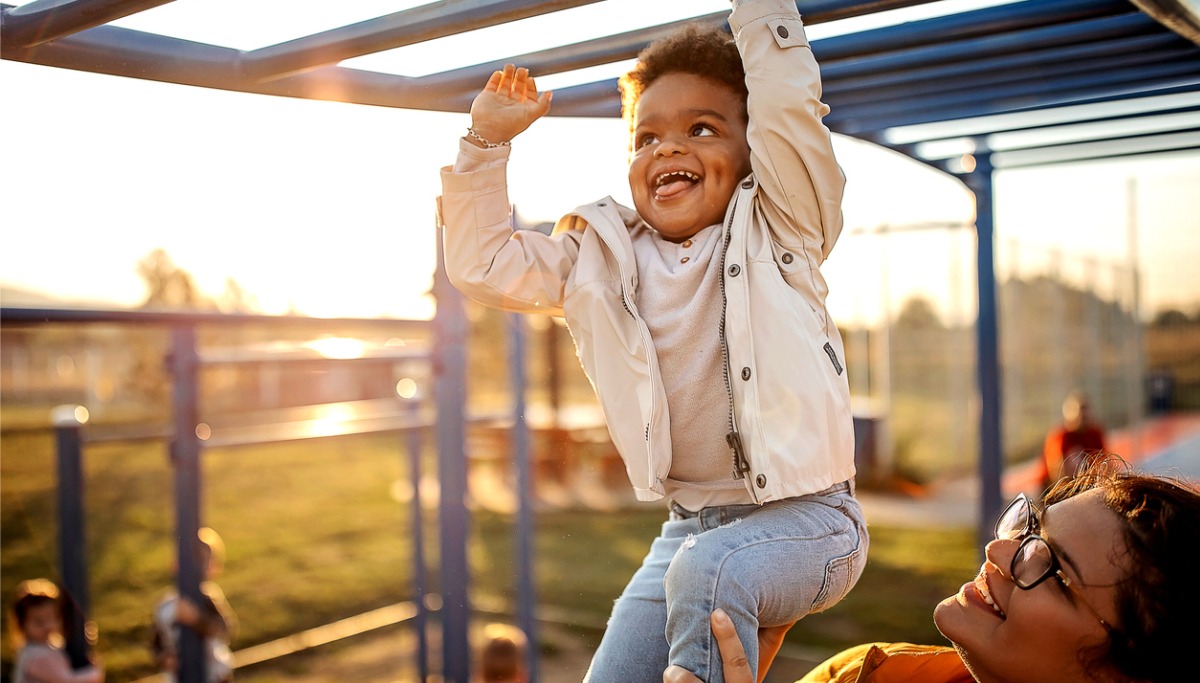 A mother and child playing on monkey bars