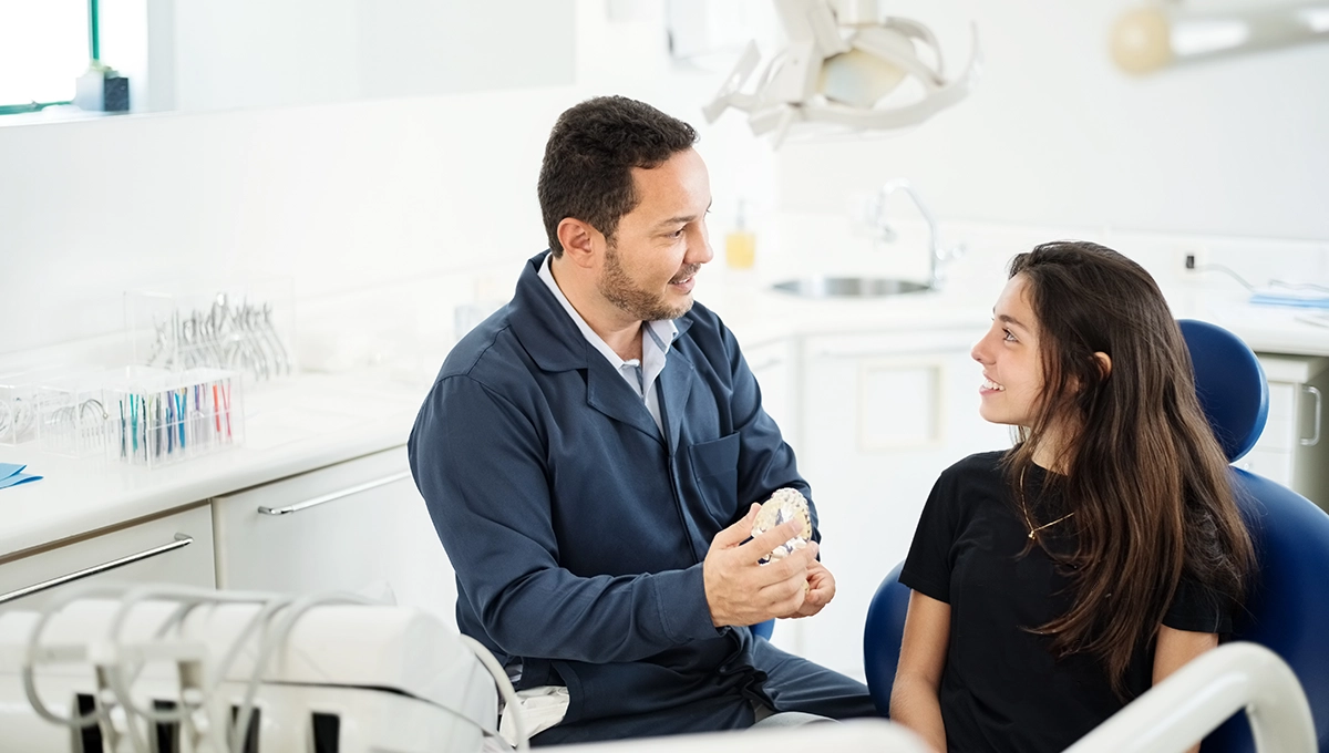 A dentist showing a patient a model of the human mouth