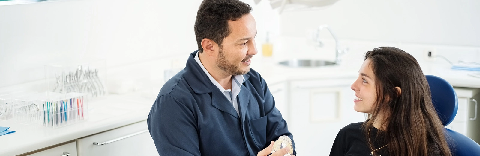 A dentist showing a patient a model of the human mouth