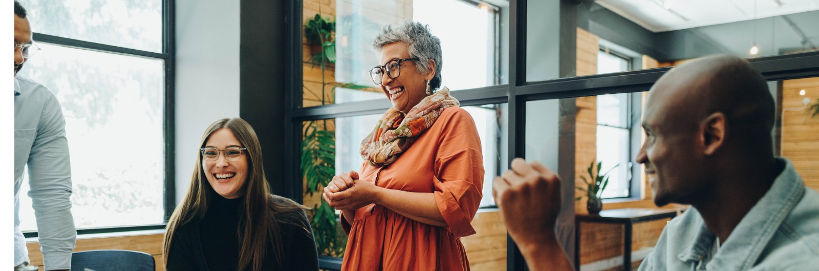 A group of employees gathered around a computer and laughing